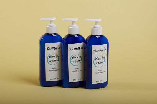 A photo of 3, 8-fluid ounce blue lotion bottles with white pumps on a yellow background labelend KalamaSoap Forest Oud & Balsam Scented Hand & Body Lotion