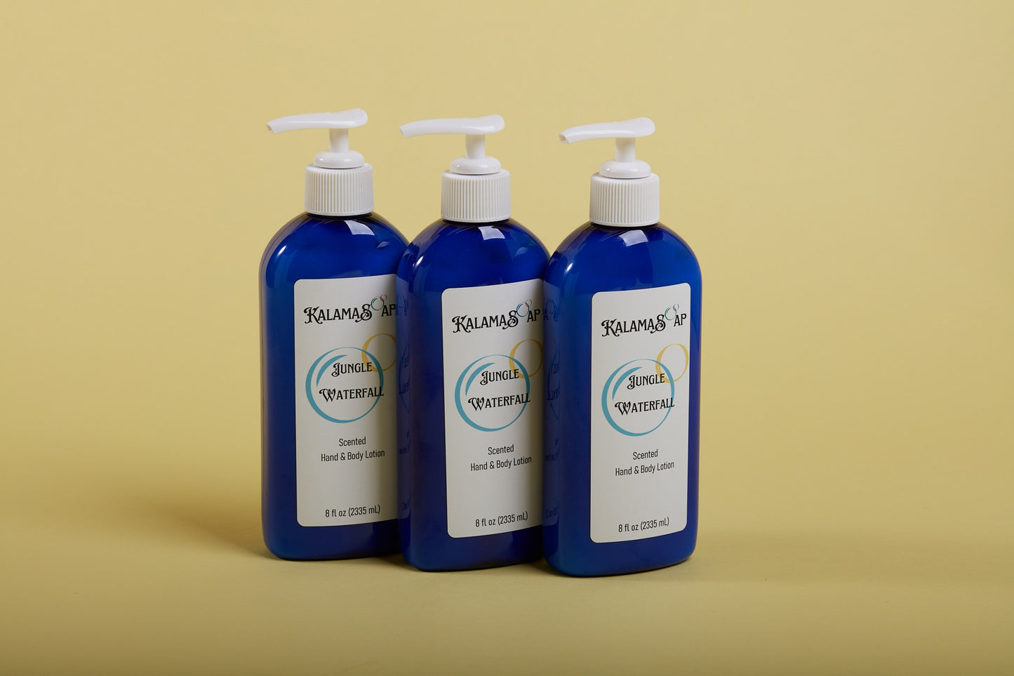 A photo of 3, 8-fluid ounce blue lotion bottles with white pumps on a yellow background labelend KalamaSoap Jungle Waterfall Scented Hand & Body Lotion